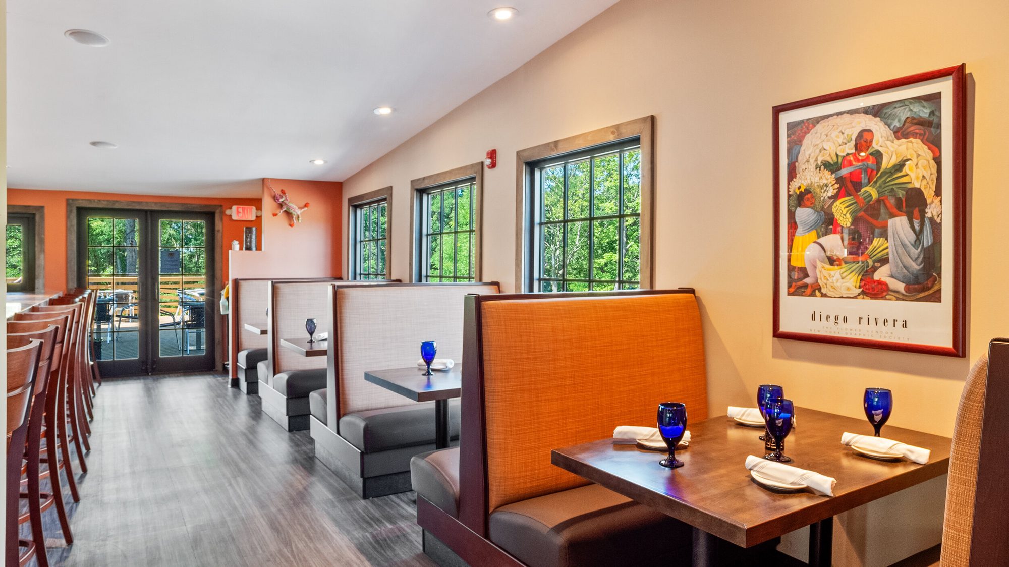 Booth seating along an orange wall, artwork above