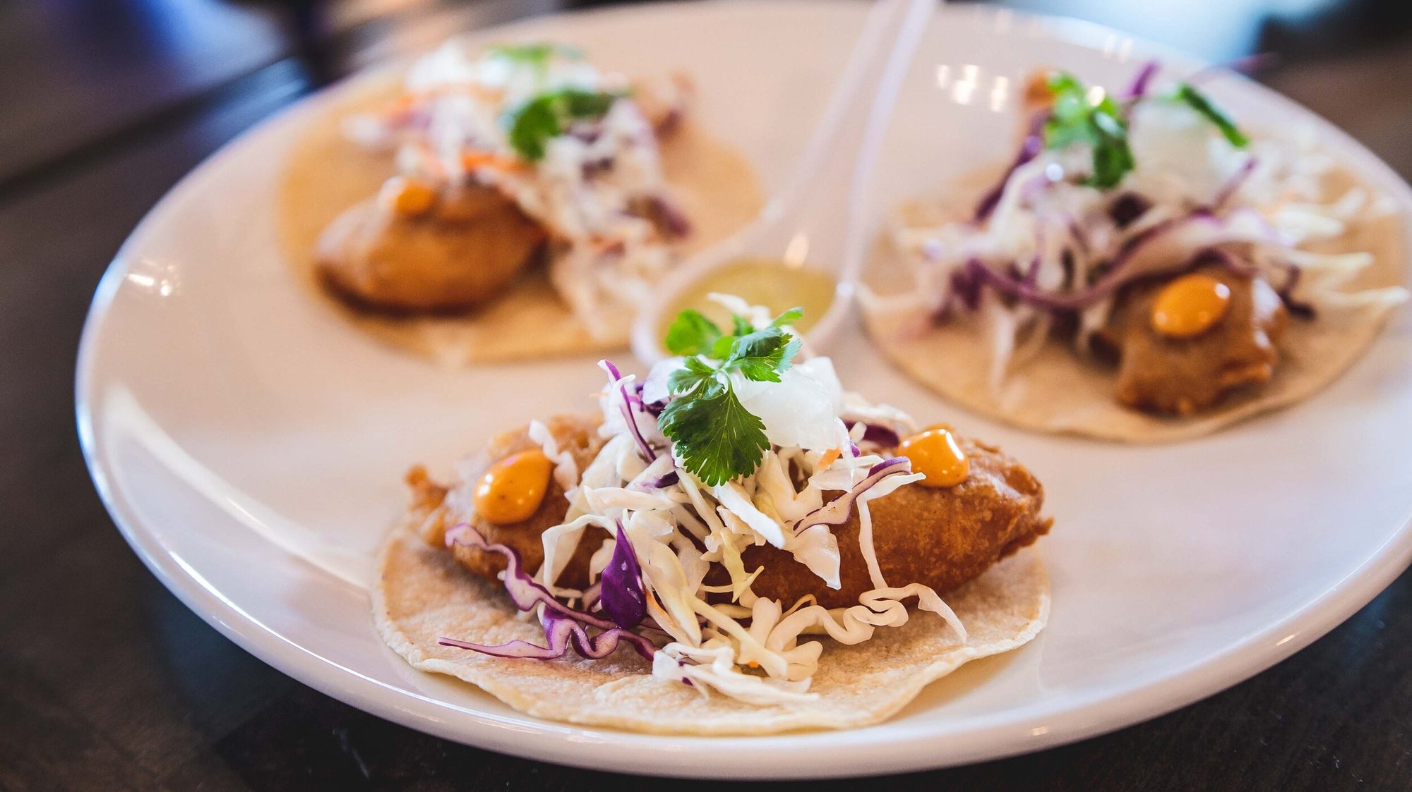 Fish tacos plated with slaw and crema