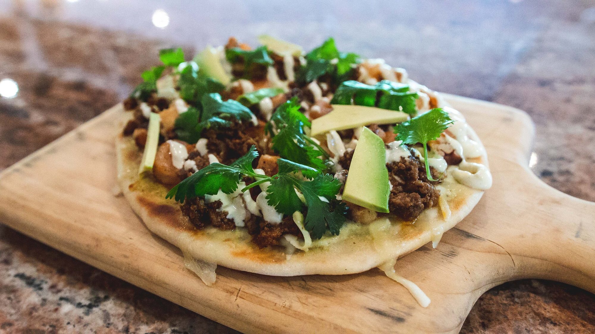 A flatbread topped with avocado and crema