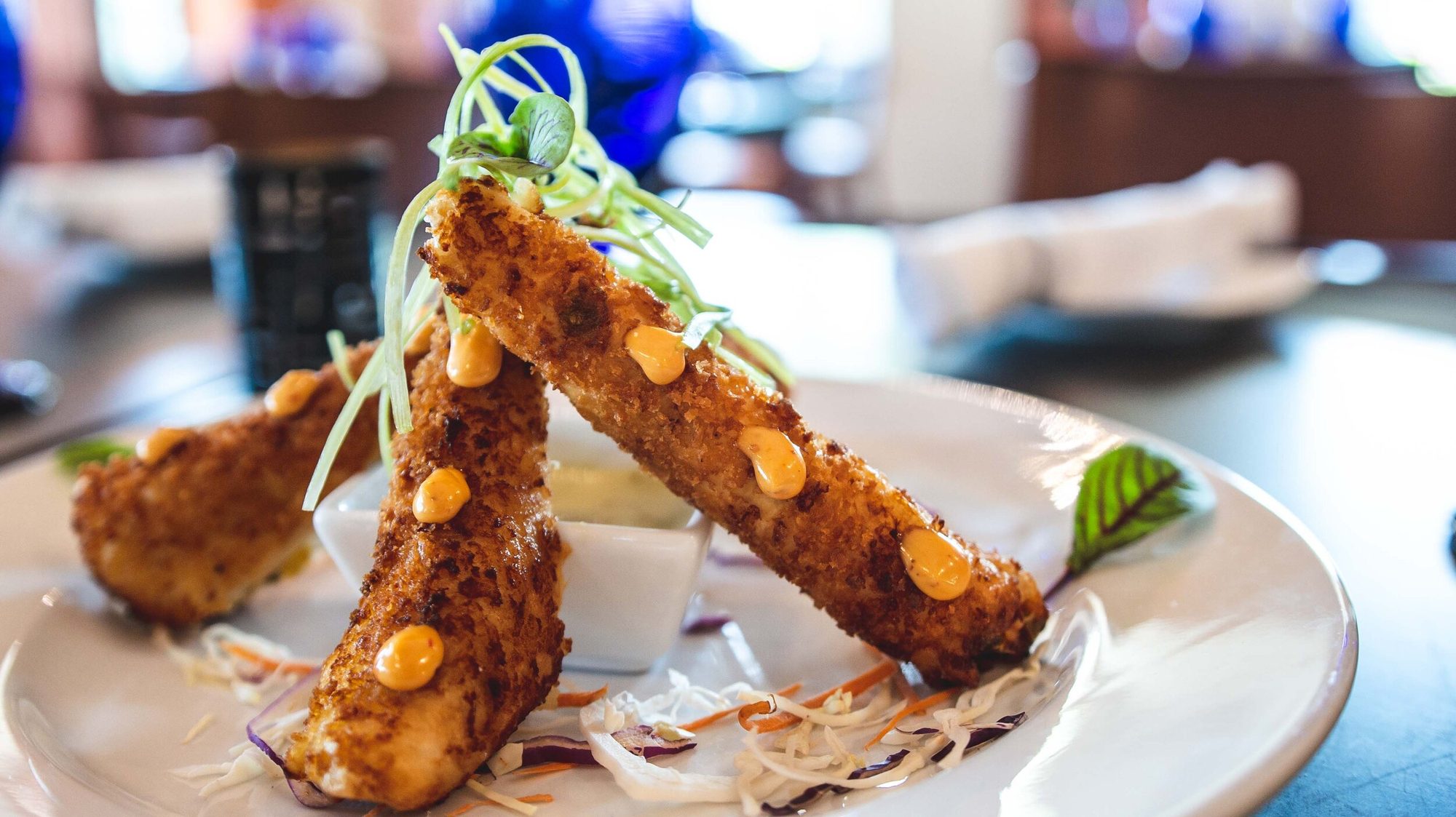 Fried queso sticks stacked over slaw
