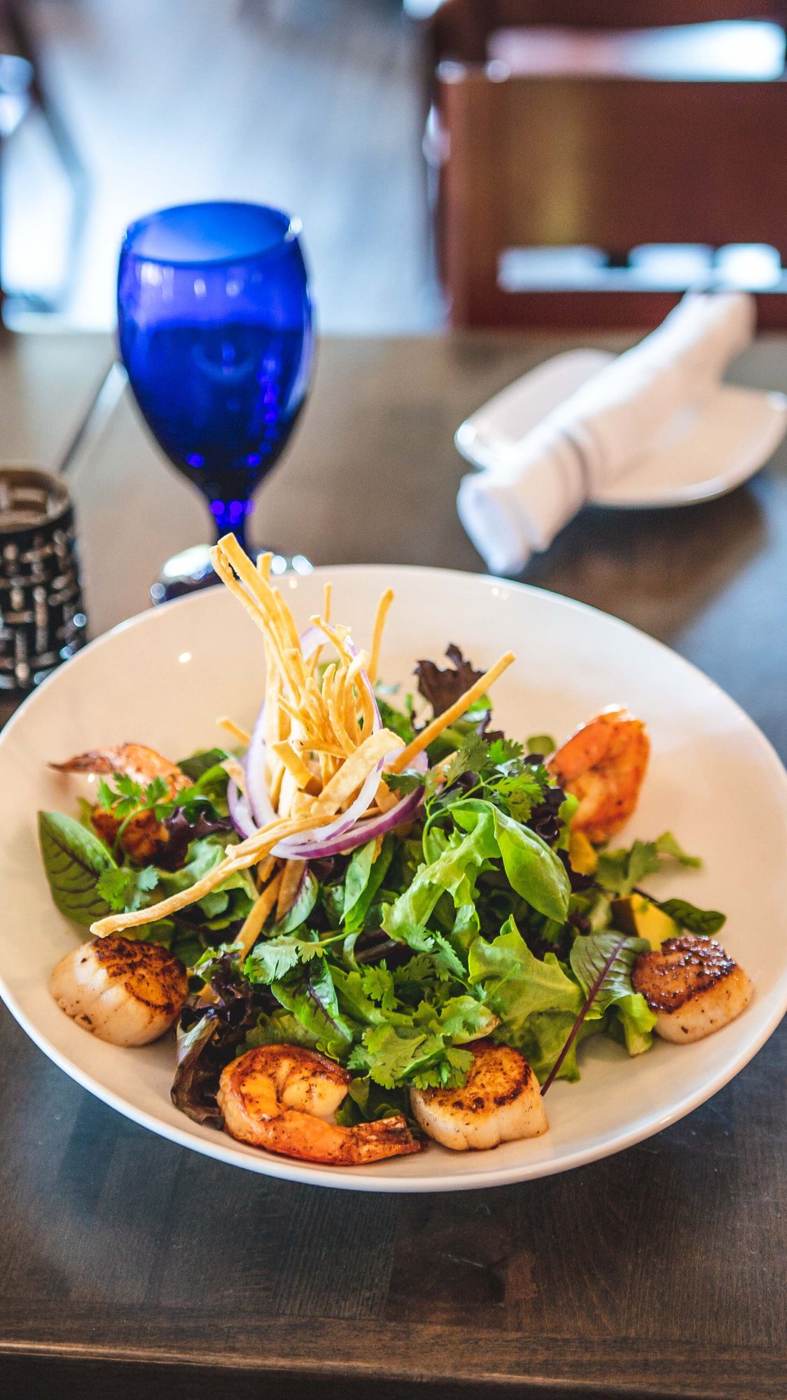 Salad served beside a cobalt water glass