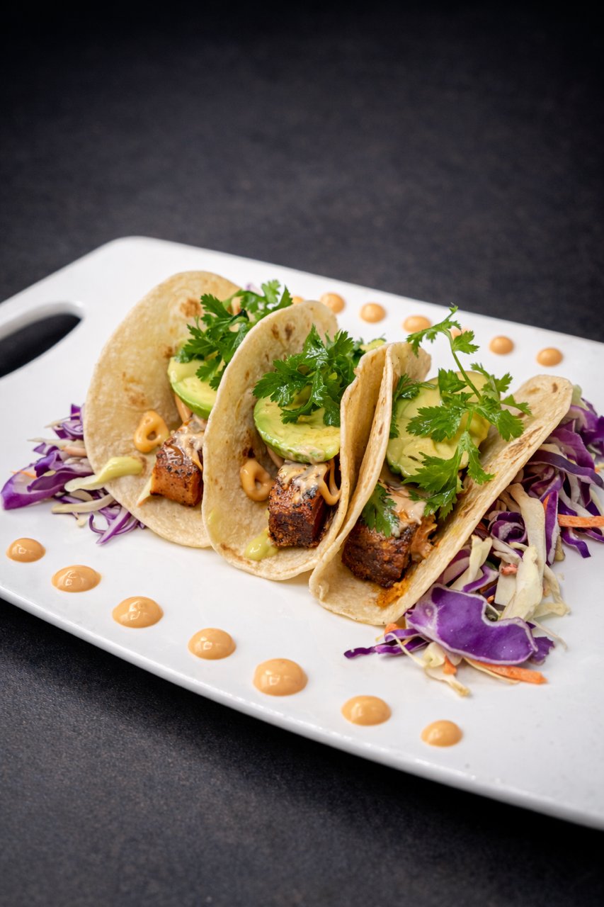 Street tacos with cabbage, cucumber and chipotle-mayo on a white plate