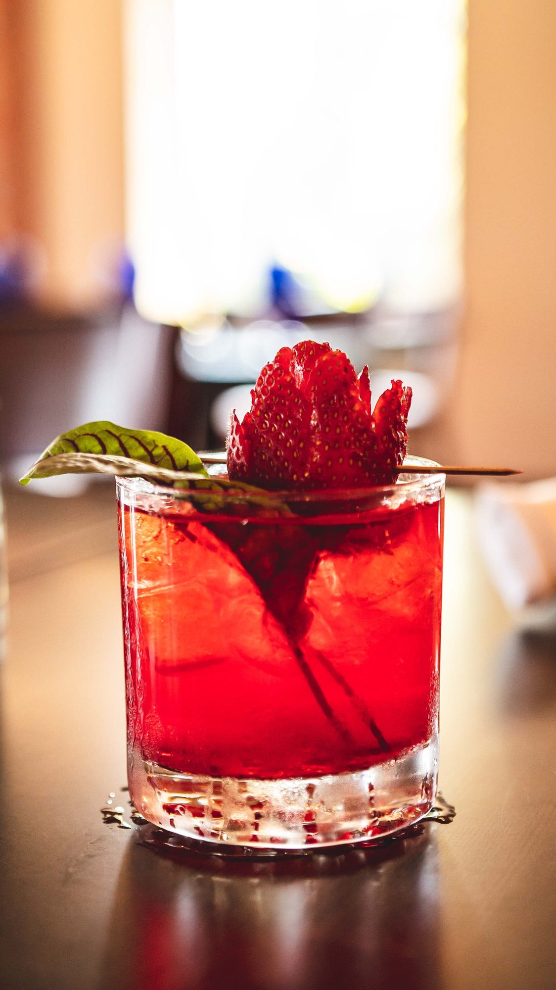 A red cocktail garnished with a strawberry