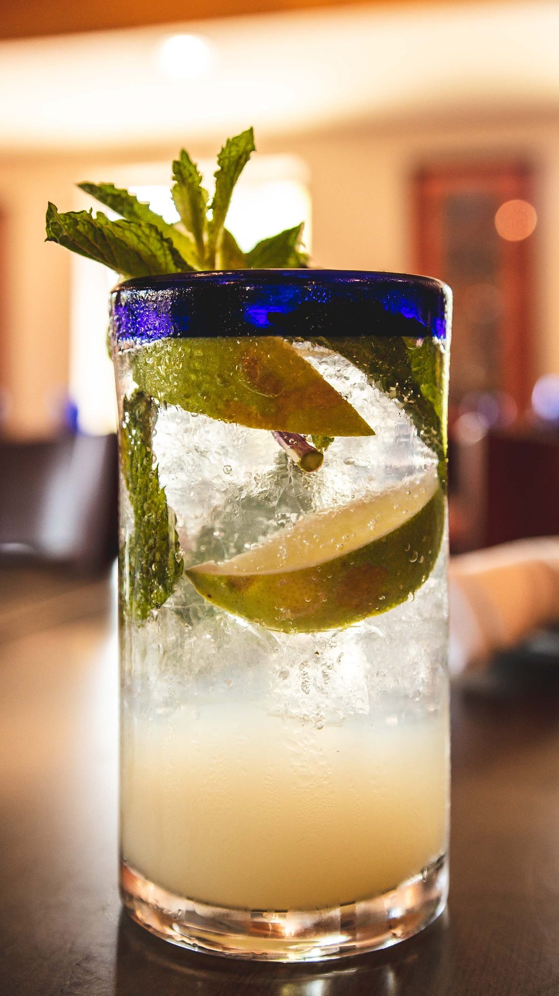 A margarita with a blue salt rim and a wedge of lime