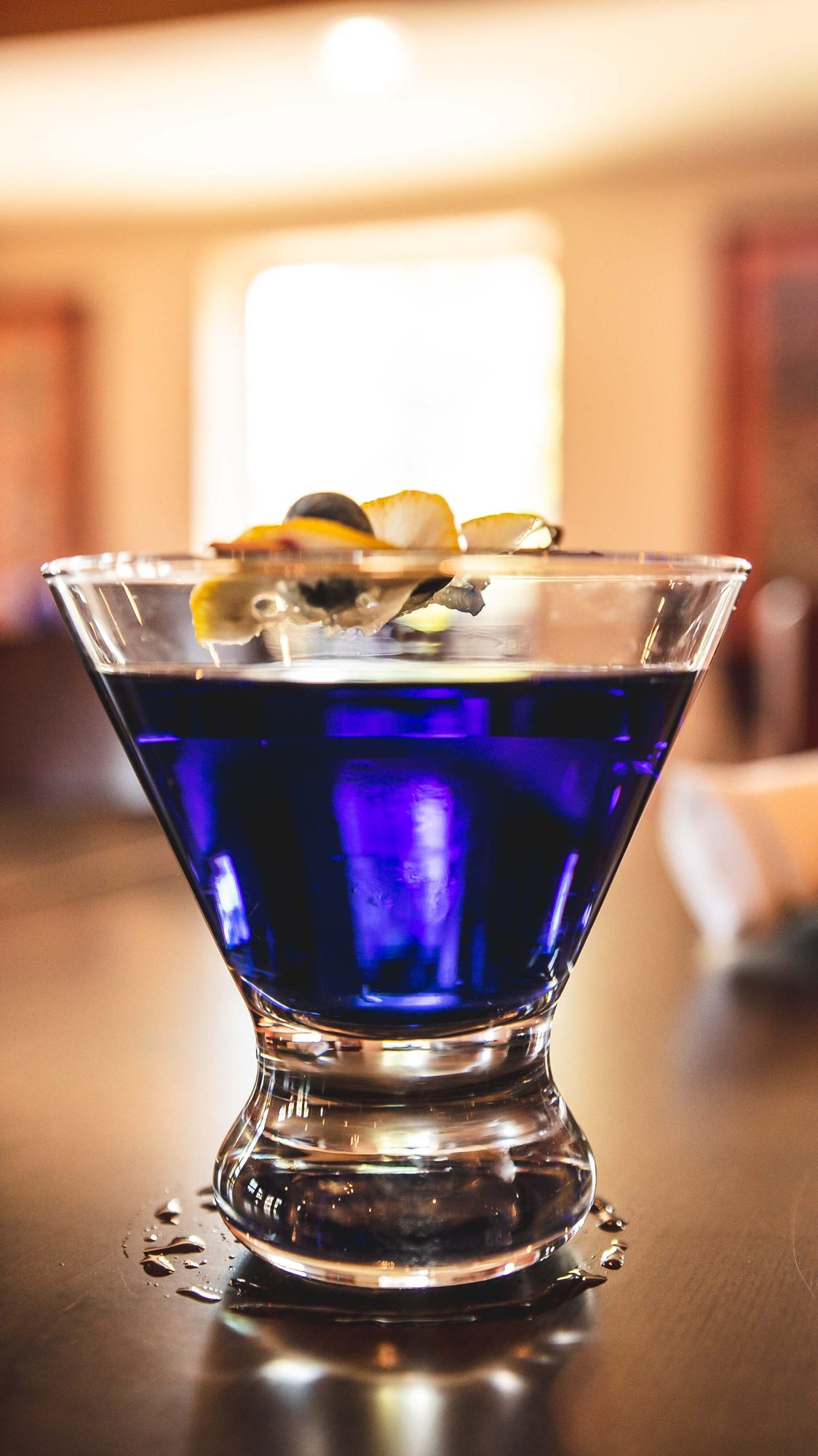 A cobalt martini glass with olives