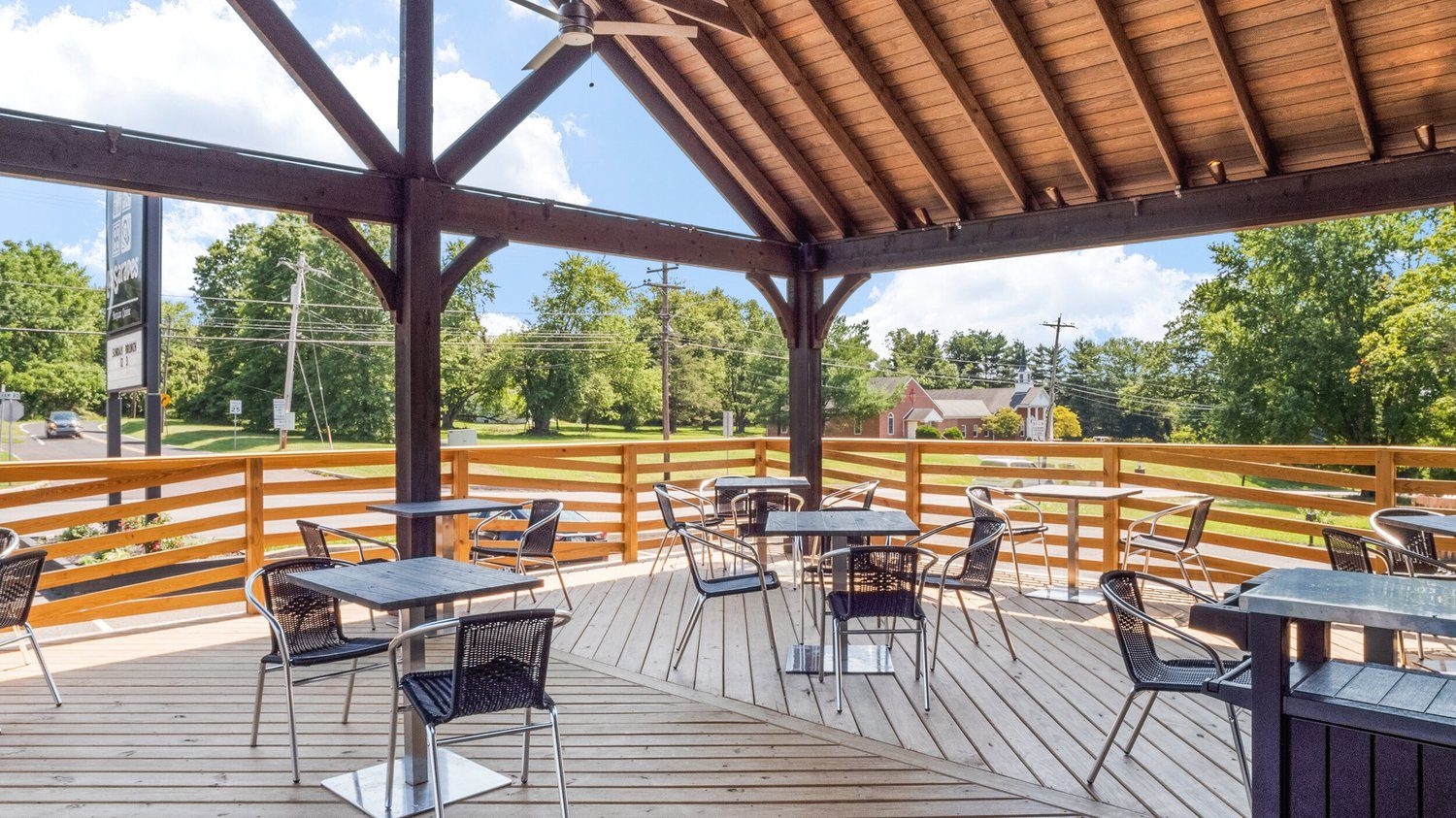 The covered patio under its timber roof, tables along the rail