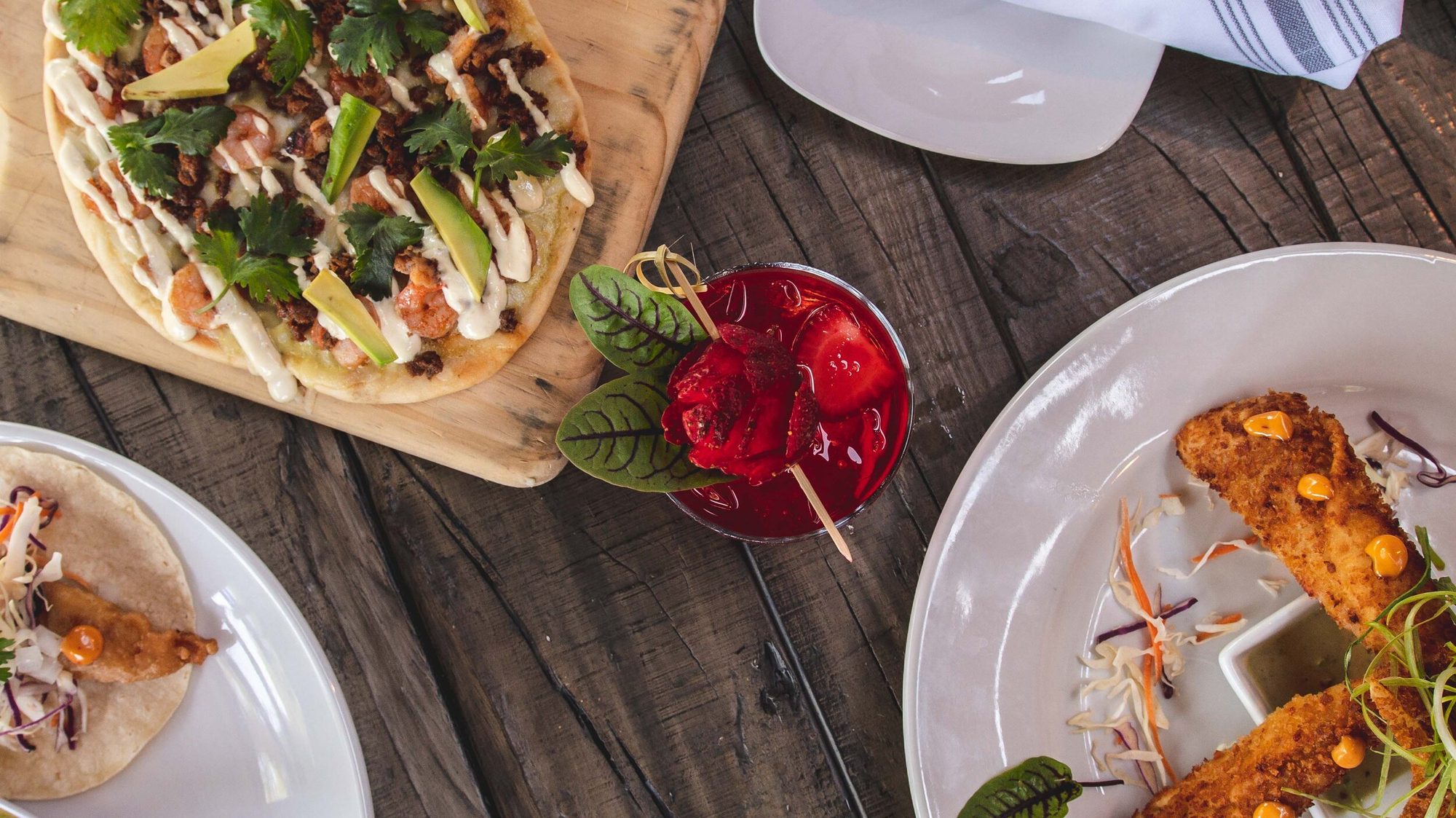 Tacos, a flatbread and a red drink across the table